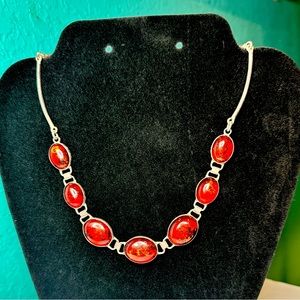 Red necklace embedded with gold flakes surrounded with a silver chain